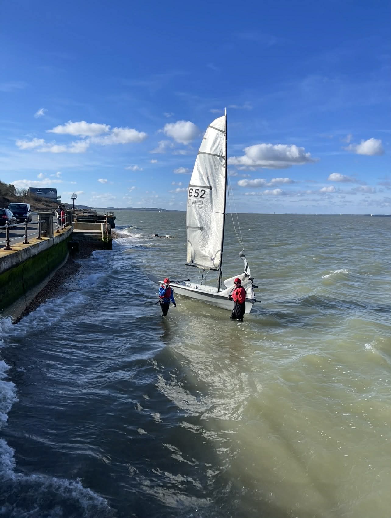 Two people wading in water next to a small boat