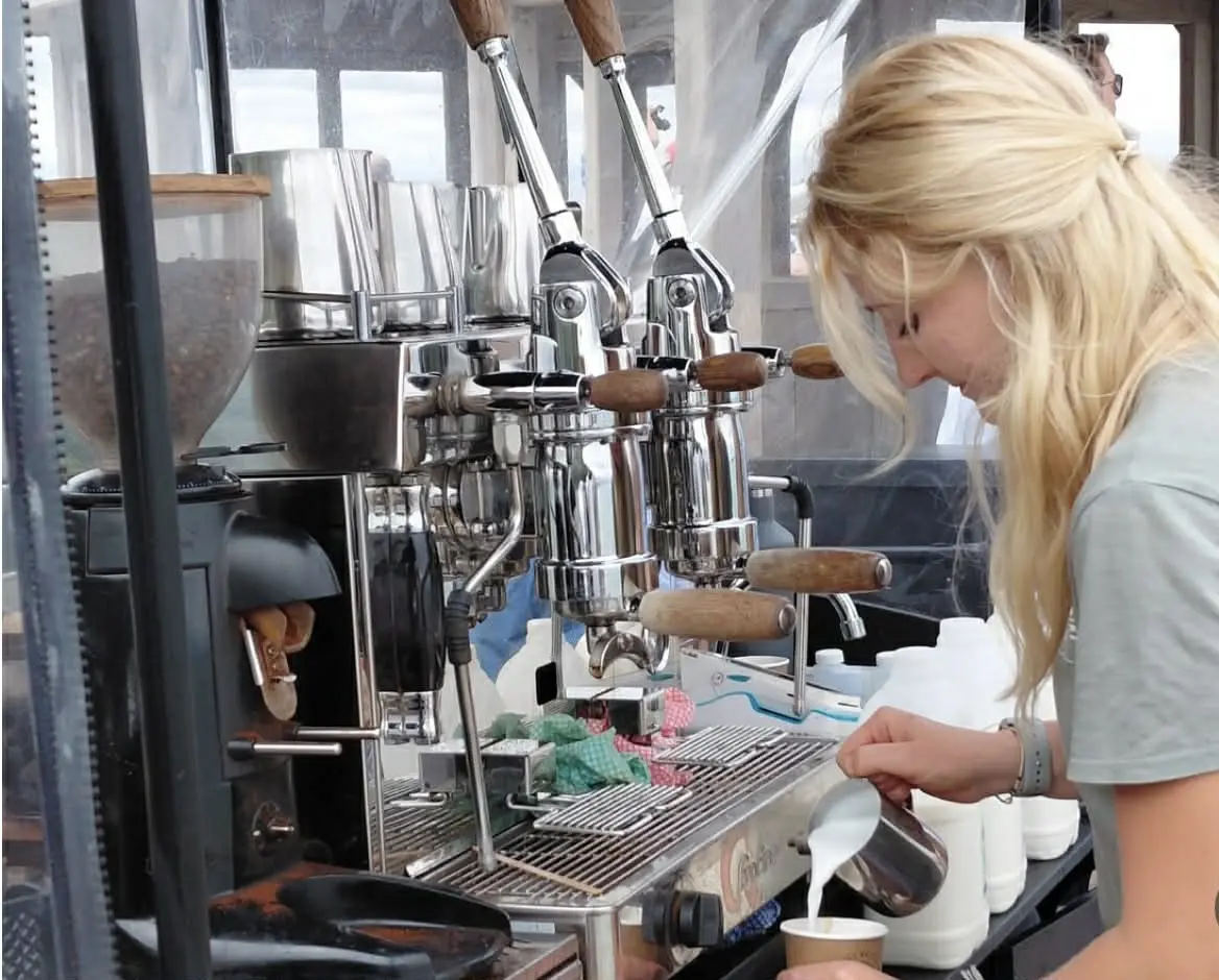 Lady pouring milk into a coffee cup